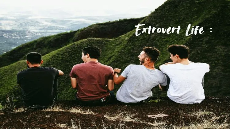 Four friends are sitting on a mountaintop, laughing and joking. written "Extrovert Life".