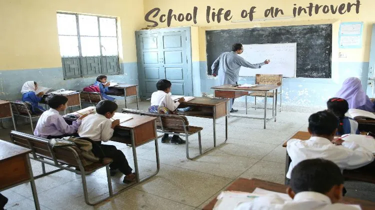 The teacher is teaching the students in the classroom. The words "School Life of an Introvert" are written on the wall.